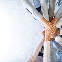 Veel handen die op elkaar liggen als teken van samenwerking
